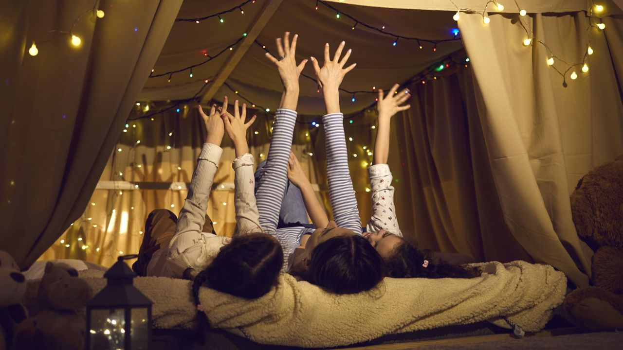 Børn der overnatter i telt indenfor med lyskæder
